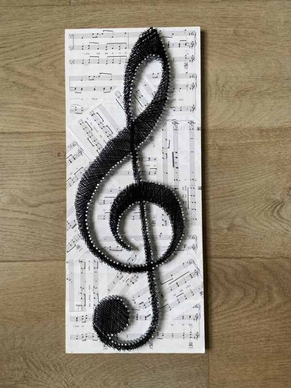 Muzikale string-art G-sleutel met bladmuziek achtergrond