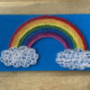 Regenboog op twee witte wolken String-Art op een blauwe achtergrond